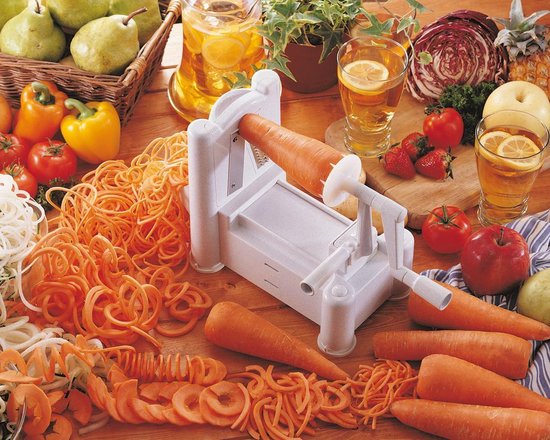 Een witte spiraalsnijder snijdt een oranje wortel in dunne slierten, omringd door verse groenten en fruit.