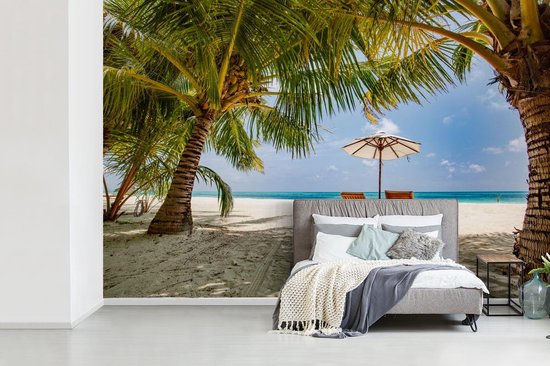 Chaises longues entre les palmiers sur une plage de Bali fotobehang