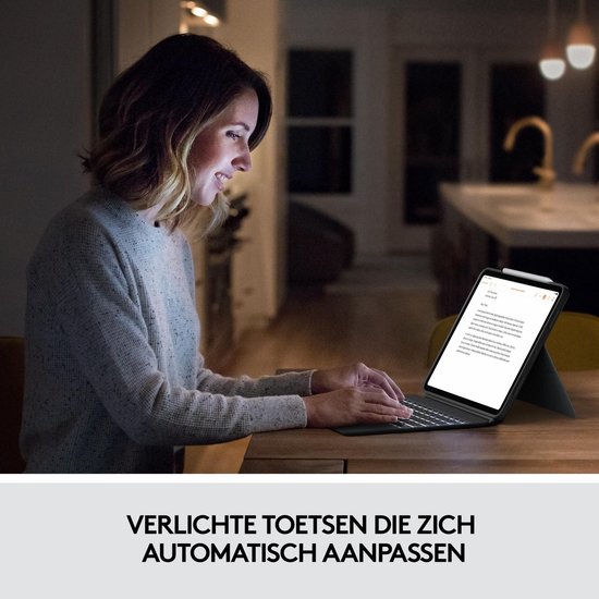 Vrouw die typt op een verlicht toetsenbord van een iPad Pro in een schemerige kamer.