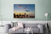 Silhouette d'un avion au dessus des palmiers Toile 120x80 cm - Tirage photo sur toile (Décoration murale salon / chambre)