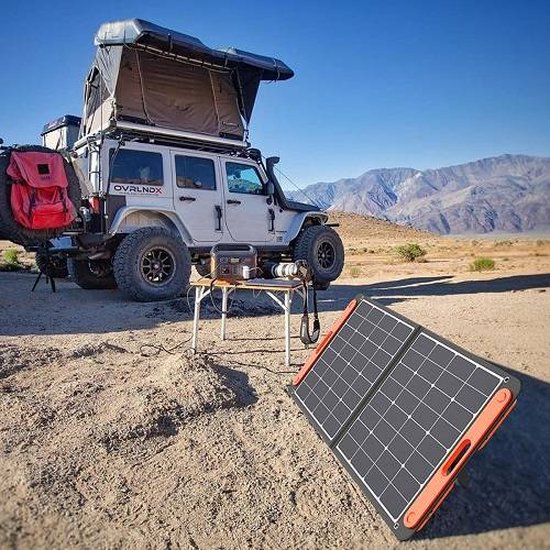Off-road voertuig met daktent, Jackery Explorer 1500 krachtcentrale en opvouwbaar zonnepaneel op rotsachtig terrein met bergen op achtergrond.