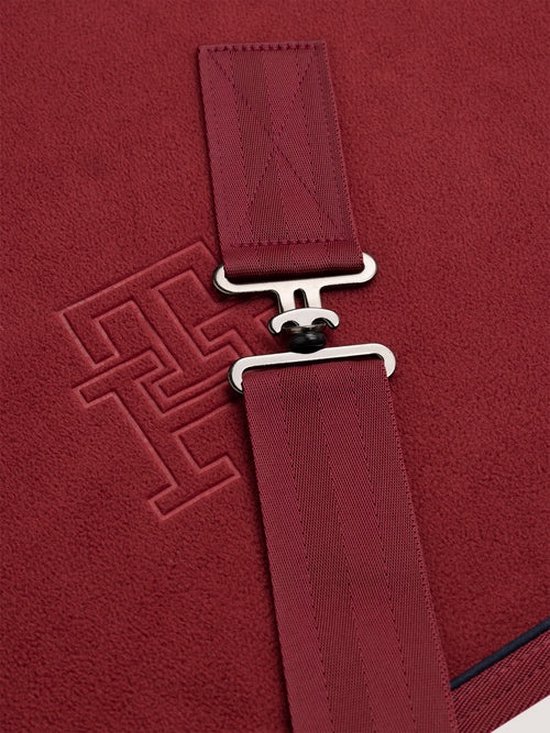 Rode deken met TH monogram en stoffen band met gesp.