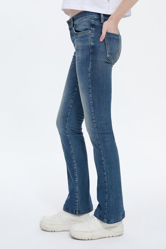 Zijaanzicht van een model in een donkerblauwe flared spijkerbroek.