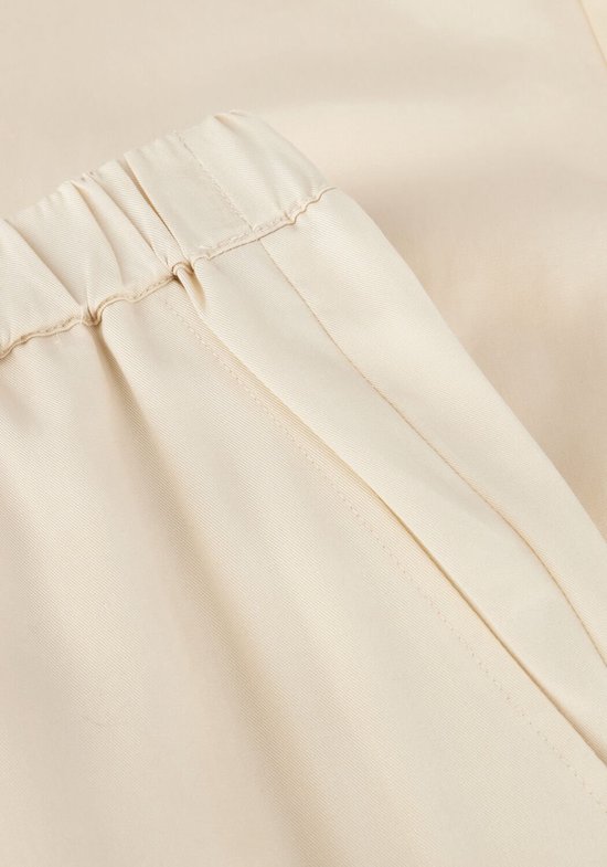 Gedetailleerde close-up van de crème wijde culotte broek, de elastische tailleband en de tailleband.