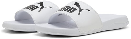 Paar witte slippers met zwarte Puma-logo's op de bandjes.