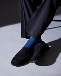 Gros plan sur des mocassins noirs en daim et des chaussettes bleu vif.