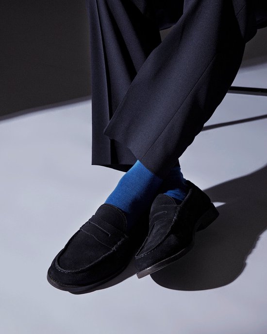 Gros plan sur des mocassins noirs en daim et des chaussettes bleu vif.
