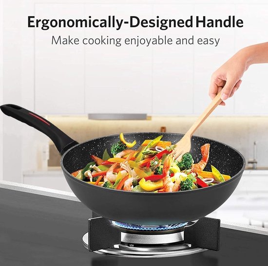 Wok noir antiadhésif rempli de crevettes, légumes et nouilles, sur une cuisinière à gaz.