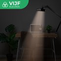 Zwarte bureaulamp verlicht een bureau met laptop en planten.