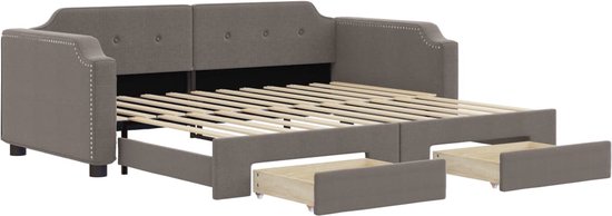 Grijze stoffen slaapbank met open lades en onderschuifbed, met knopen op de rugleuning.