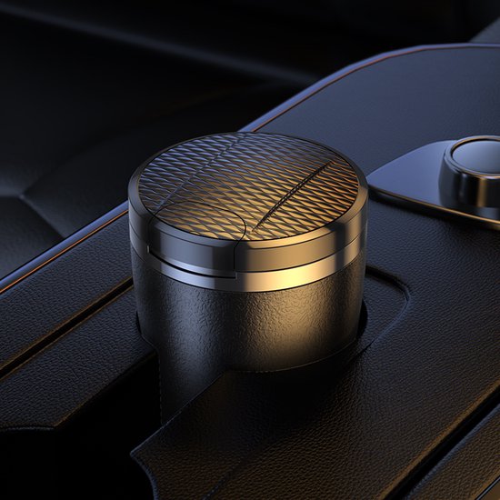 Zwarte aut asbak met een geruit, goudkleurig metalen deksel en zilveren rand, in een auto console.