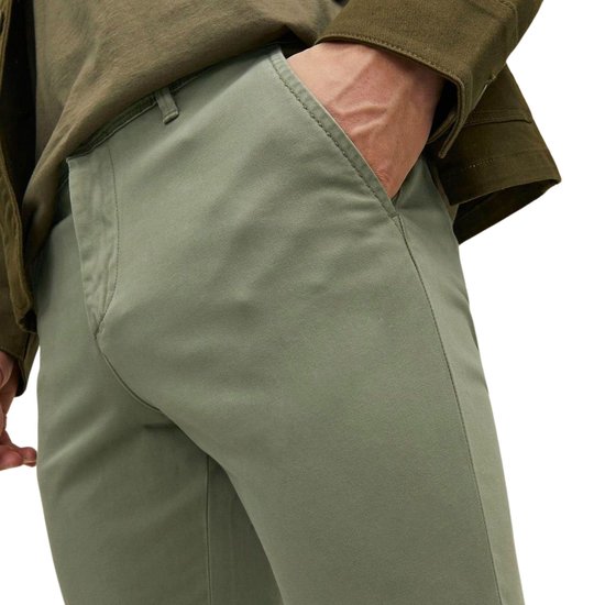 Man met hand in zak van lichtgroene chino.