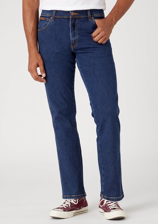 Man in donkerblauwe Wrangler jeans, gedragen met bordeauxrode sneakers.
