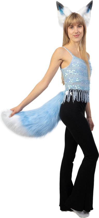 Vrouw met blond haar, draagt een blauw pailletten topje, zwarte broek, en beweegt een lichtblauwe pluizige staart met witte punt.