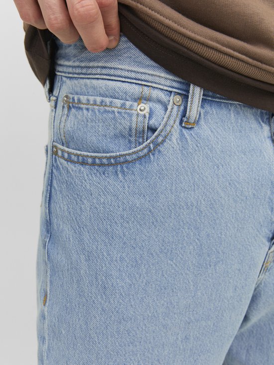 Close-up van de voorkant van een lichtblauwe jeans met zakken en knopen.