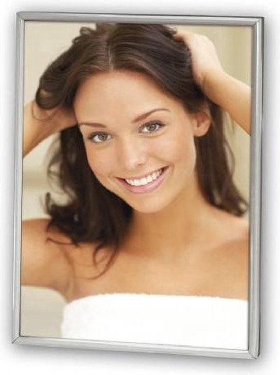Femme aux cheveux foncés, une serviette blanche autour de la poitrine, souriante.