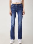 Model draagt donkerblauwe LTB Jeans Fallon flared jeans met lichte wassing en witte sneakers.