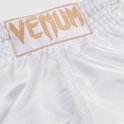 Witte Muay Thai broek van satijn met gouden VENUM logo op een patch bij de tailleband.
