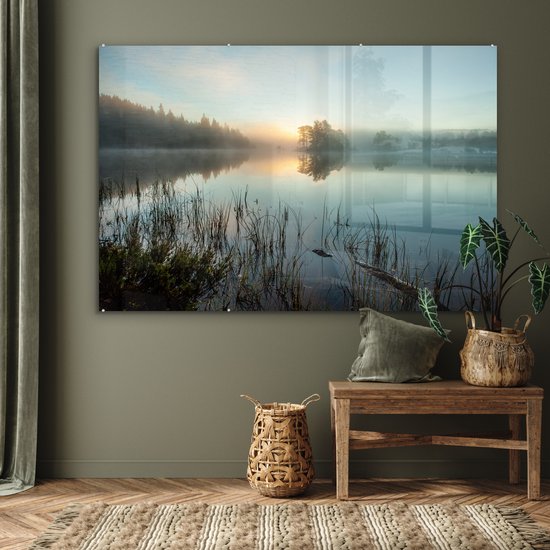 Une peinture sur verre d'un lever de soleil sur un lac brumeux, accrochée au-dessus d'un banc en bois avec des paniers.