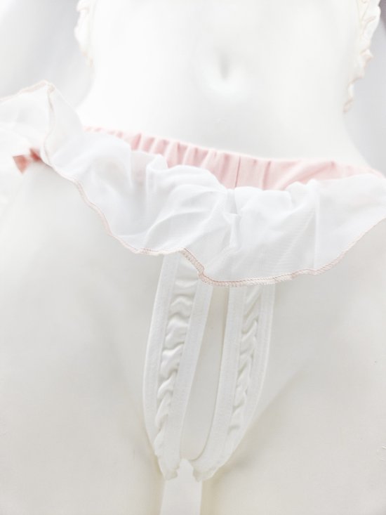 Detailopname van het witte slipje met roze ruches en een touwtjesluiting aan de voorkant. Gepresenteerd op een etalagepop.