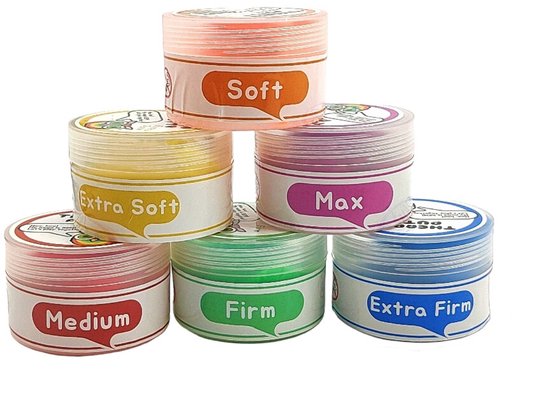 Zes potjes Therapy Putty opgestapeld: oranje Soft bovenop, geel Extra Soft en paars Max ernaast, rood Medium, groen Firm en blauw Extra Firm onderaan.