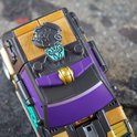 Close-up van een speelgoedauto in voertuigmodus. Zwart met gouden en paarse details, met een Decepticon-logo.