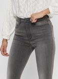 Close-up van een grijze skinny jeans met rits en knoopsluiting.