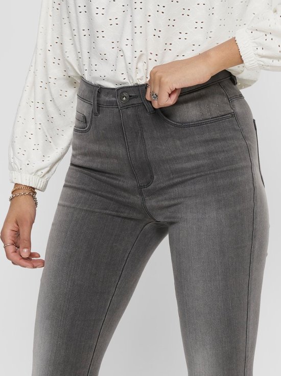 Close-up van een grijze skinny jeans met rits en knoopsluiting.