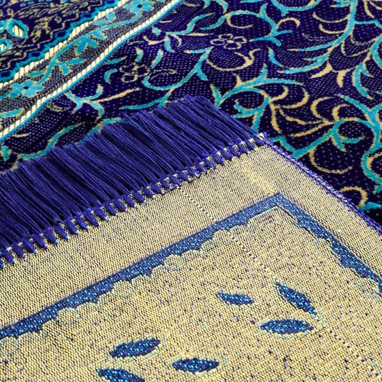 Vue détaillée du coin et des franges d'un tapis de prière bleu foncé avec des motifs de feuilles dorés et bleus.