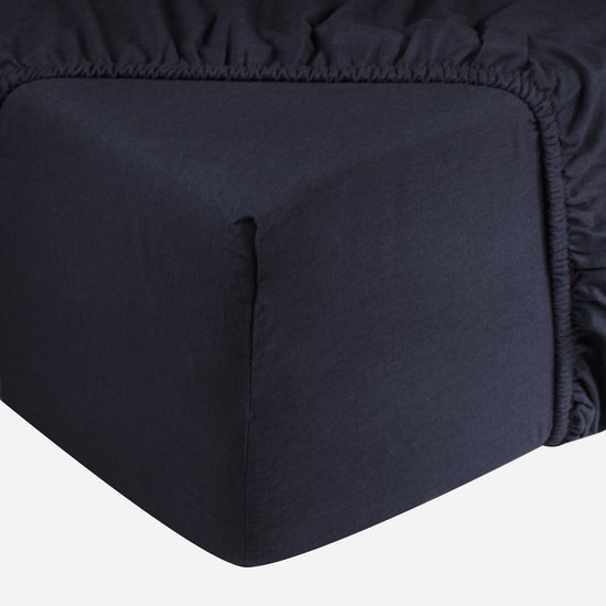 Donkerblauw jersey hoeslaken met zichtbaar elastiek aan de zijkant.