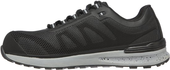 Vue latérale d'une chaussure de travail noire avec panneaux en mesh, semelle grise tachetée et bout renforcé.