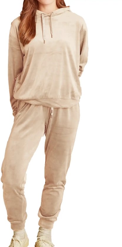 Vrouw in lichtbruin fleece trainingspak met capuchon en trekkoord, sneakers.