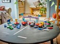Piste de course LEGO Duplo avec des voitures, des drapeaux et des accessoires sur une table.