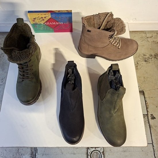 Vier paar dameslaarzen: groene en bruine chelsea boots, en groene en bruine veterlaarzen.