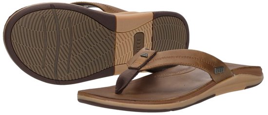 Twee bruine leren Reef teenslippers, de ene op zijn zool, de andere liggend.