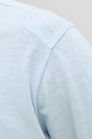 Close-up van de schoudernaad van een lichtblauwe t-shirt.