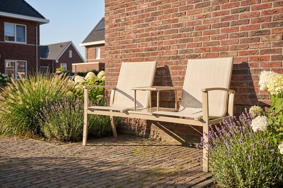 Beige aluminium tuinbank met stoffen zittingen en middenplateau, staand in de tuin tussen planten.