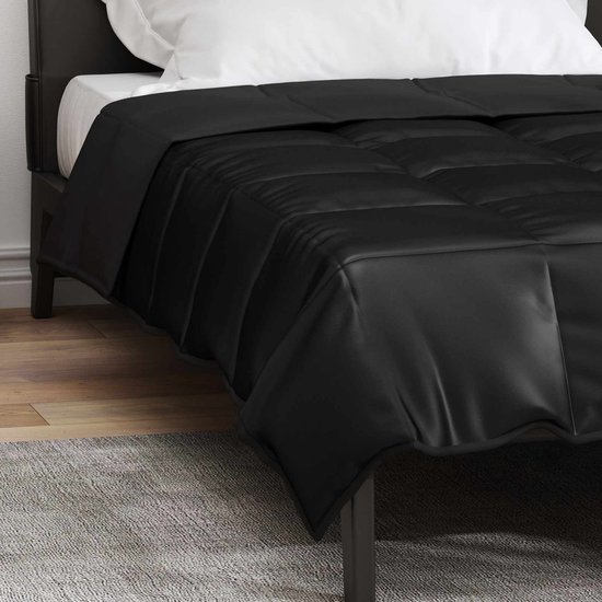 Zwart satijnen dekbed met ruitpatroon op een zwart bed.