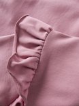 Detail van ruches op een roze sweater.