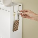 Hand haakt sleutels aan gouden en zilveren sleutelhangers aan een witte schoenenkast.