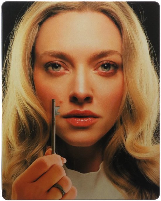 Een close-up van Amanda Seyfried met blond haar, die een sleutel vasthoudt. Ze draagt een witte top en kijkt met grijze ogen naar de camera.