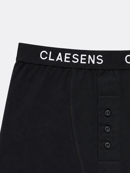 Close-up van een zwarte geribde boxershort van Claesen's met knoopjes en wit logo op de band.