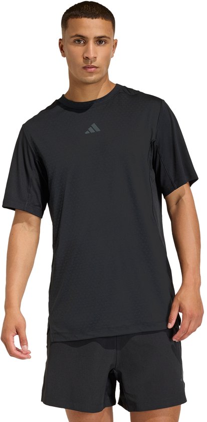 Man met zwart Adidas performance shirt met subtiel textuurpatroon en korte mouwen, gedragen met zwarte shorts.