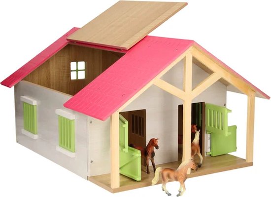 Houten paardenstal met roze dak, witte muren en groene luiken. Meerdere paarden staan in en buiten de stal.