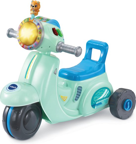 Een lichtgroene driewielige scooter met een blauw zadel en een teddybeer op het stuur.