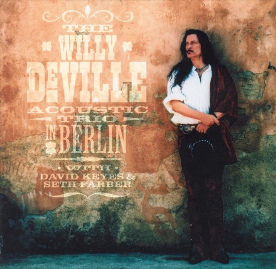 The Willy DeVille Acoustic Trio in Berlin album cover. Willy DeVille staat naast een bewerkte muur.