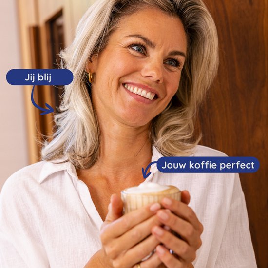 Vrolijke blonde vrouw met gouden oorbellen die een glas met melkschuim vasthoudt.