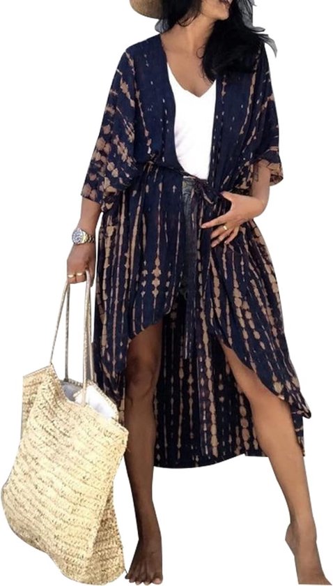 Vrouw met blauwe en beige tie-dye kimono, wit T-shirt, spijkerbroek en strooien hoed, met strandtas.