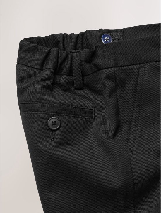 Detail van de voorkant van een zwarte broek met knoop en steekzak.