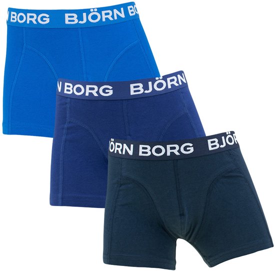 Drie Björn Borg boxershorts in de kleuren blauw, marineblauw en donkerblauw, met witte merknaam op de band.